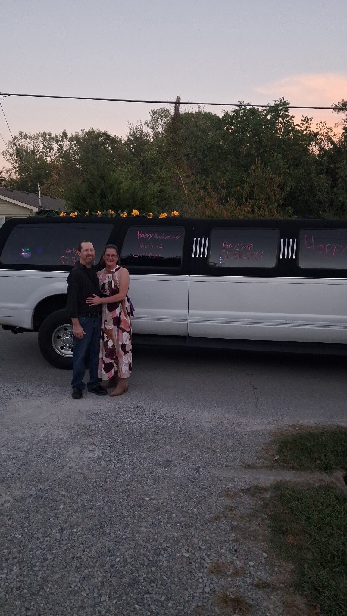 Couple celebrating their anniversary in front of the Nashville Karaoke Rides stretch limo with flowers on the roof